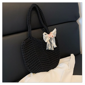 Detail of hand-woven black tote bag featuring delicate white lace bow accessory