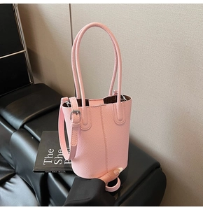 Close-up of pink bucket bag with litchi texture on a black leather seat background