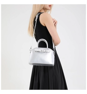 Chic silver shell-shaped handbag with adjustable strap shown on a black dress model