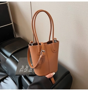 Close-up of brown litchi grain leather bucket bag with silver metal buckles and handles