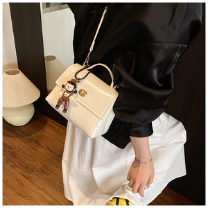 Dettaglio borsa a mano bianca in pelle cerata lucida con chiusura in metallo e charm
