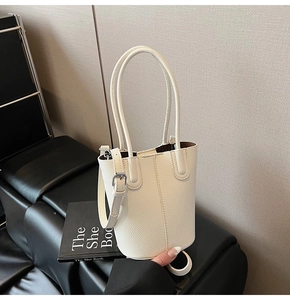 Close-up of cream white lychee texture bucket bag with silver buckle on black bench