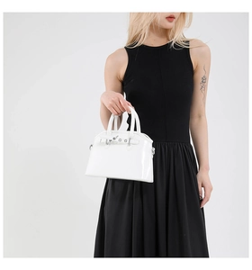 Detailed view of glossy white patent leather handbag with polished silver metal buckle