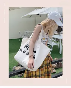 Outdoor shot of a white canvas tote bag with black Aloha print and dual handles