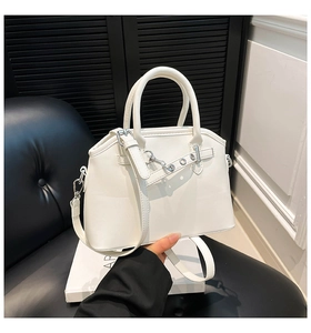 White faux leather handbag with silver hardware and chain detail on a display stand