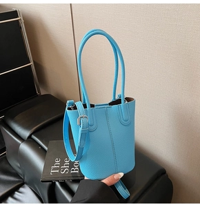 Close-up of sky blue lychee grain leather bucket bag with elegant dual handle detail