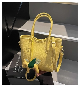 Close-up of yellow pebble leather bucket bag with top handles and golden horse charm