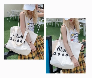 Detail of white canvas tote bag showing Aloha print and reinforced shoulder strap texture