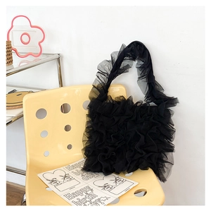 Detail of black ruffled tulle tote bag with pleated lace design on a yellow artistic chair