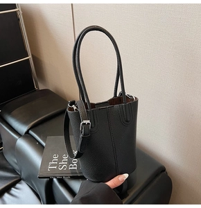 Close-up of black leather bucket bag featuring lychee texture and silver buckle detail