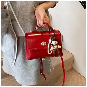 Dettaglio borsa rossa in pelle cerata con chiusura dorata e catena di perle