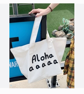 Close-up of white canvas tote bag with black Aloha print and wide shoulder strap