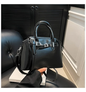 Close-up of black glossy oil wax leather handbag with silver hardware and adjustable strap