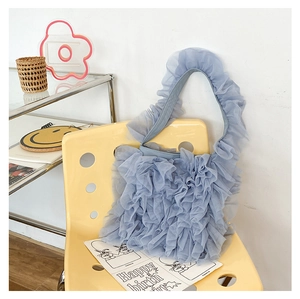 Detail of blue pleated mesh ruffle tote bag featuring layered textures on a yellow chair