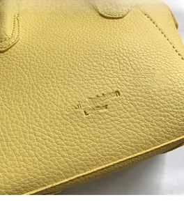 Detailed macro view of yellow pebble grain leather and embossed logo stitching