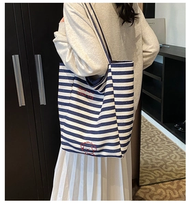 Detail of blue and white striped canvas tote bag with red dog embroidery shown on model