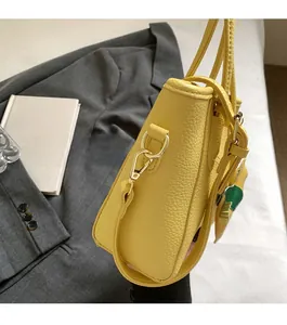 Detail view of lychee grain leather side profile and pale gold metal hooks of handbag