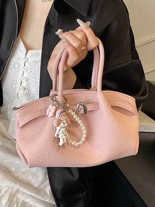 Pink lychee grain leather handbag with a metal twist lock and a cute girl doll pendant