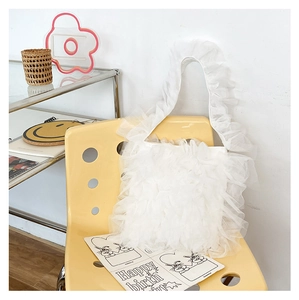 Detailed close-up of white layered mesh ruffle tote bag on a yellow designer chair