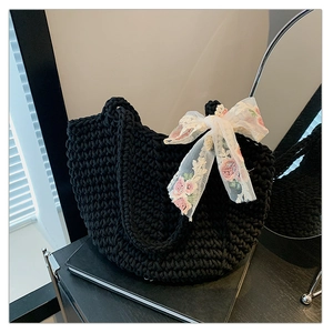 Detail of hand-woven black tote bag with white lace bow and floral embroidery