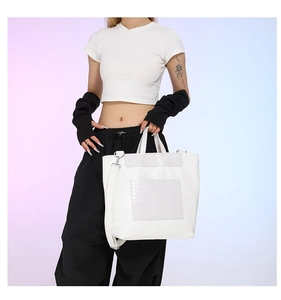Detail of white crocodile embossed leather tote bag with stylish skull patchwork design