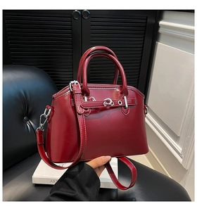 Detail of burgundy leather Boston bag with silver horsebit buckle and round top handles