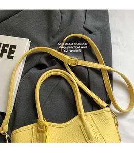 Detail of yellow lychee leather bag with adjustable strap and golden metal hardware