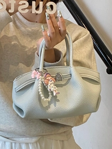 Light blue pleated bucket bag with pearl chain and cartoon charm shown by a model
