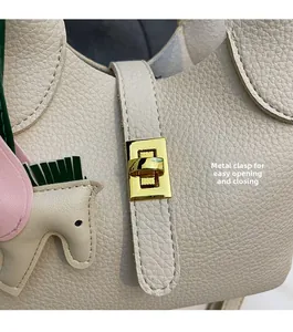 Gros plan du sac seau en cuir grainé beige avec fermoir doré et breloque petit cheval