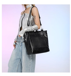 Detail view of large black tote bag with skull embossing and crocodile texture pocket