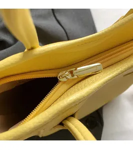 Macro detail of high-quality golden zipper and litchi grain leather on yellow bucket bag