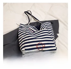 Detail of blue and white striped canvas tote bag featuring a cute red dog embroidery