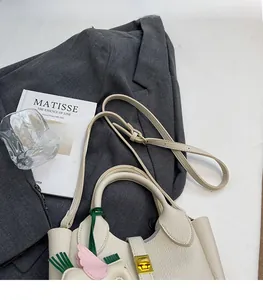 Détail d'un sac seau en cuir grainé avec fermoir rotatif doré et bandoulière réglable