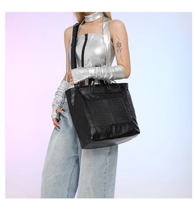 Close-up of black tote bag with skull embossing, crocodile texture and adjustable strap