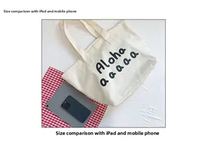 Top view of large cream canvas tote bag showing size scale compared to iPad and phone
