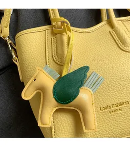 Macro detail of a yellow lychee leather pegasus charm with green wings on a handbag