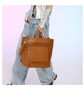 Detail view of brown crocodile texture tote bag with skull embossing and silver hardware