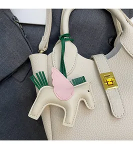Détail du charm pégase en cuir sur un sac seau beige avec motif en litchi poli