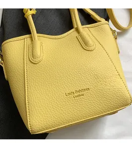 Detail shot of bright yellow lychee texture leather handbag with branded logo stamp