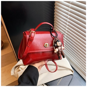 Dettaglio borsa vintage rossa con chiusura dorata e accessorio con ciondolo a bambolina