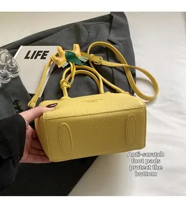 Detail of yellow lychee leather bag with anti-wear base studs and horse charm