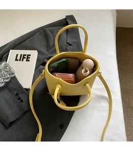 Macro shot showing large interior capacity of yellow bucket bag with daily essentials