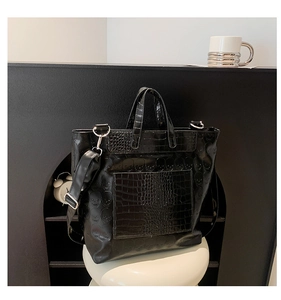 Close-up of black crocodile pattern leather tote bag featuring a 3D skull relief and silver hardware