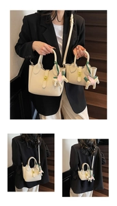 Vue détaillée des sacs seau en cuir crème avec texture grainée et garnitures dorées