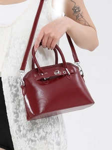 Glossy burgundy shell-shaped handbag with top handles and silver hardware crossbody strap