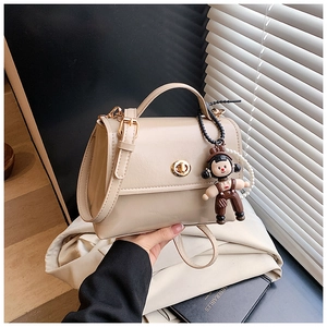 Dettaglio borsa beige in pelle cerata con chiusura dorata e ciondolo di perle
