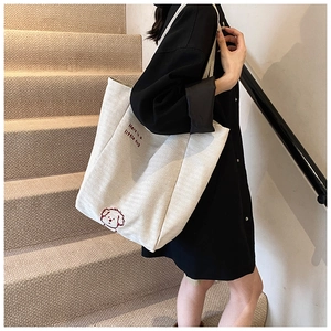 Detail of minimalist cream canvas tote bag featuring a cute red dog embroidery and text