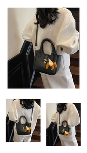 Détail du sac seau noir en cuir grainé avec un pendentif pégase jaune élégant