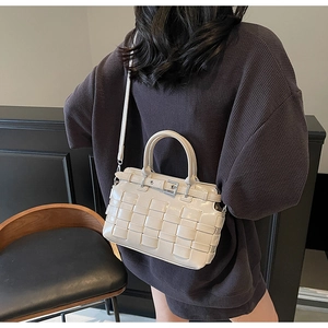Dettaglio della borsa a secchiello intrecciata beige con fibbia metallica sul retro