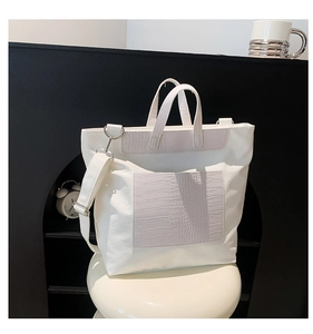 Close-up of white tote bag featuring embossed skull pattern and crocodile texture details